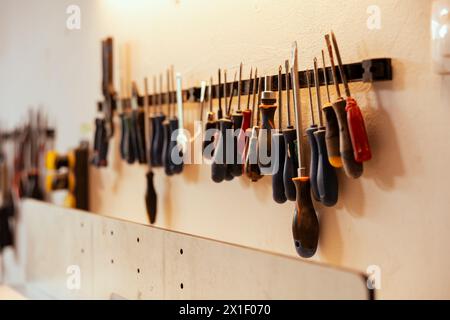 Gros plan de divers outils de travail du bois sur rack dans l'atelier utilisé pour la réparation ou la création d'objets en bois. Ciseaux, tournevis, clé et pinces sur le mur dans le studio de menuiserie Banque D'Images