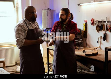 Artisan et collègue regardant sur les schémas techniques pour fabriquer un objet en bois commandé. Fabricant et collègue regardant les plans pour exécuter le projet de menuiserie d'assemblage de meubles Banque D'Images