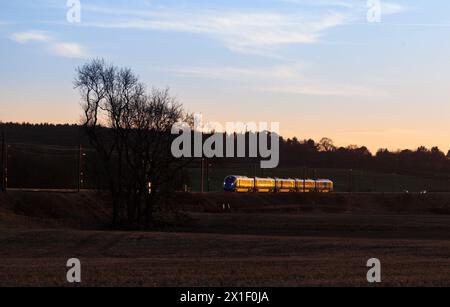 Train électrique FirstGroup Lumo Class 803 de l'opérateur en accès ouvert sur la ligne ferroviaire principale de la côte est à 4 voies en Écosse scintillant au coucher du soleil Banque D'Images