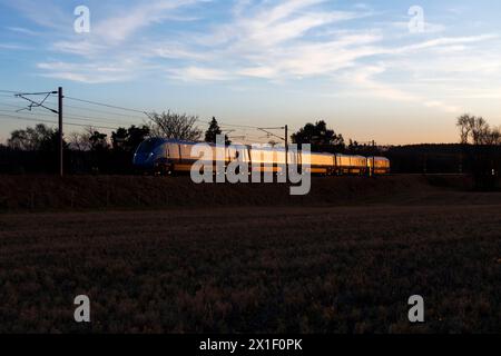 Train électrique FirstGroup Lumo Class 803 de l'opérateur en accès ouvert sur la ligne ferroviaire principale de la côte est à 4 voies en Écosse scintillant au coucher du soleil Banque D'Images