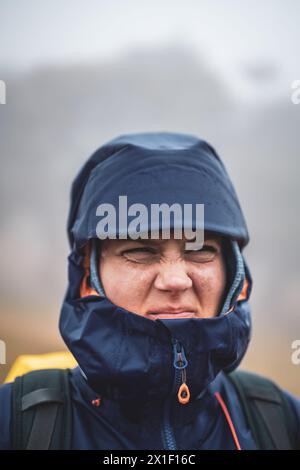 Description : vue avant de Backpacker dans des vêtements imperméables regardant insatisfait dans la distance. Forêt de Fanal, île de Madère, Portugal, Europe. Ventilateur Banque D'Images