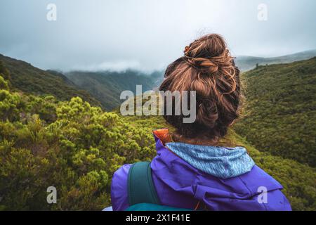 Description : femme touriste avec sac à dos profite de la vue sur une vallée envahie par une journée nuageuse et brumeuse. 25 Cascades de Fontes, Île de Madère, Portug Banque D'Images