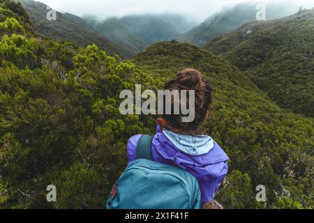 Description : plan d'angle supérieur de touriste féminine avec sac à dos jouant la vue sur une vallée envahie par la végétation sur une journée nuageuse brumeuse. 25 chutes de Fontes, fou Banque D'Images