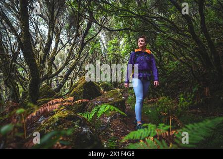 Description : femme touriste avec sac à dos aime marcher à travers un chemin de forêt moussue et rocheuse, laruel un jour de pluie. 25 Cascades Fontes, île de Madère Banque D'Images