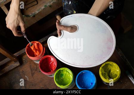 Vue d'en haut des pots de peinture acrylique de couleurs et palette en plastique utilisé pour la peinture dans le studio d'art. Copier l'espace. Artiste et concept de passe-temps Banque D'Images