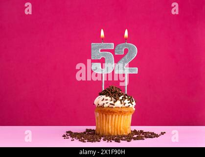 Célébration d'anniversaire avec numéro de bougie 52 - cupcake au chocolat sur fond rose Banque D'Images