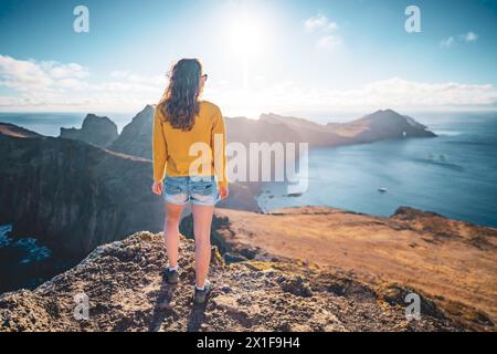 Description : vue arrière d'un touriste regardant les contreforts d'une île volcanique dans l'océan Atlantique depuis un point de vue panoramique matinal. São Louren Banque D'Images