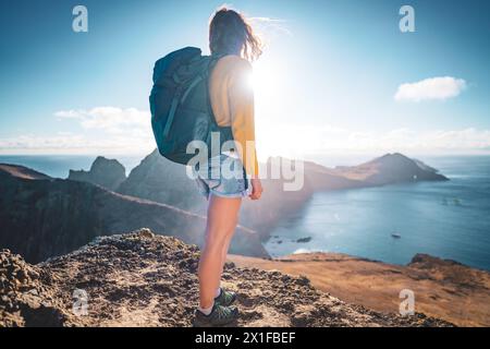 Description : vue arrière à angle bas d'un routard sportif debout au sommet des contreforts d'une île dans l'océan Atlantique le matin. São Lourenço Banque D'Images