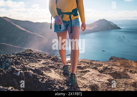 Description : vue de face à angle bas des jambes de routard touristique marchant sur le dessus des contreforts d'une île dans l'océan Atlantique dans la matinée. São Louren Banque D'Images