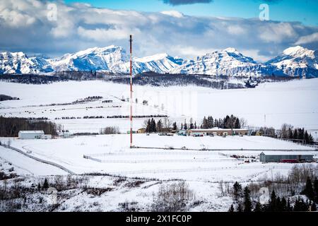 Torche de l'industrie pétrolière et gazière surplombant les collines enneigées avec les montagnes Rocheuses de l'Alberta en arrière-plan dans l'Ouest canadien. Banque D'Images