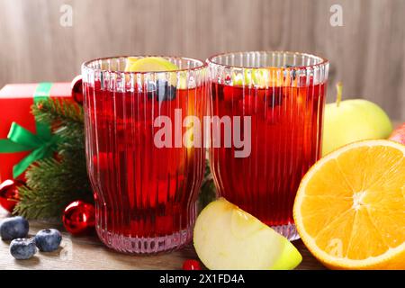 Boisson aromatique de Sangria dans des verres, des ingrédients et un décor de Noël sur la table Banque D'Images