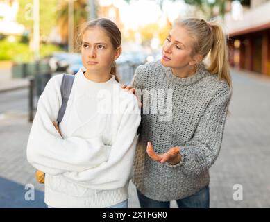 Une jeune fille agacée marchant dans la rue de la ville avec une mère inquiète qui la reproche Banque D'Images