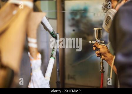 Homme portant un masque de protection respiratoire spray peignant un cadre de vélo dans son atelier. Composition à focalisation sélective. De vraies personnes qui travaillent. Banque D'Images