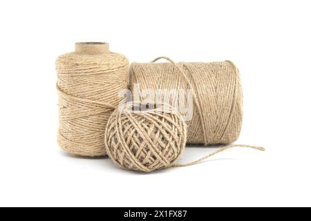 Trois bobines de ficelle de jute isolées sur fond blanc, chacune variant en taille, fabriquées à partir de matériaux naturels de jute Banque D'Images