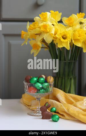 Bouquet de jonquilles dorées dans un vase en verre sur fond de bois vert avec espace pour le texte. Banque D'Images