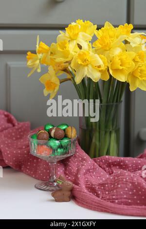 Bouquet de jonquilles dorées dans un vase en verre sur fond de bois vert avec espace pour le texte. Banque D'Images