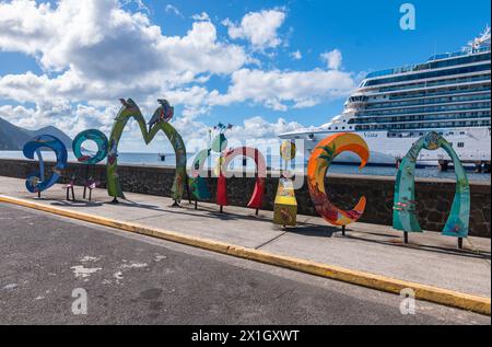 Roseau, Dominique - 24 novembre 2023 : signe de mot Dominique devant le navire Oceania Cruises Vista dans le port de croisière de Roseau. Banque D'Images