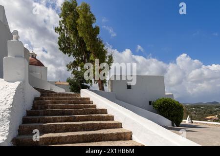 Les marches de pierre montantes de l'église Puig de Missa à Ibiza, en Espagne, mènent à sa façade blanche emblématique et à son dôme en terre cuite, sur fond bleu Banque D'Images