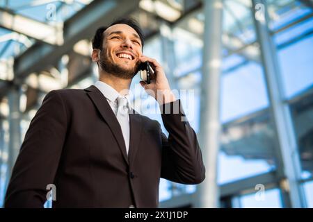 Jeune professionnel confiant engagé dans une conversation téléphonique à l'extérieur Banque D'Images