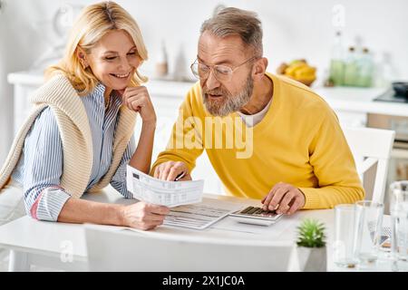 Un homme mûr et une femme dans des vêtements confortables sont assis dans la cuisine, engrossés dans la lecture du journal ensemble. Banque D'Images