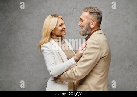 Homme et femme élégants et matures dans une tenue élégante posent ensemble sur un fond gris. Banque D'Images