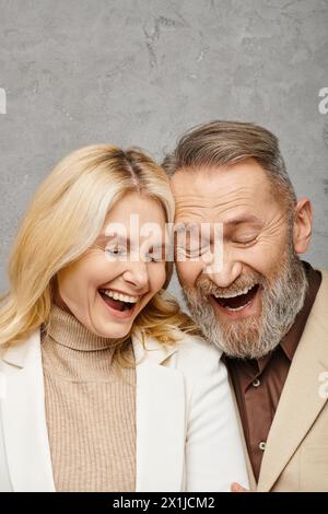 Un homme et une femme mûrs, tous deux élégamment habillés, partageant un moment de joie en riant ensemble. Banque D'Images