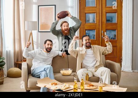 Trois hommes joyeux et interraciaux en tenue décontractée s'assoient ensemble sur le dessus d'un canapé, profitant d'un grand moment dans l'autre compagnie. Banque D'Images