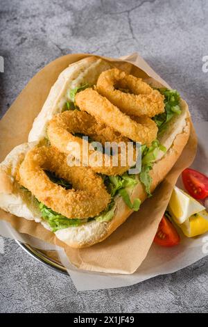 Calmars frit dans du pain avec des légumes verts sur le côté. Sandwich au calmar Banque D'Images