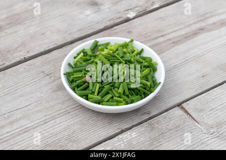 Bol blanc avec ​​chives tranché sur un fond en bois clair Banque D'Images