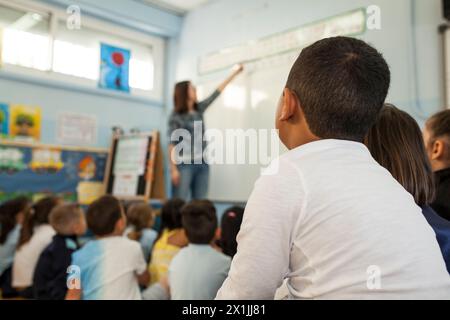 les enfants de l'école primaire écoutent l'explication de l'enseignant dans une classe scolaire Banque D'Images