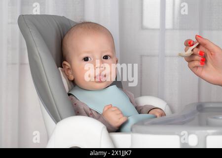 La première alimentation avec de la purée de fruits pour un bébé garçon de 6 mois. Banque D'Images