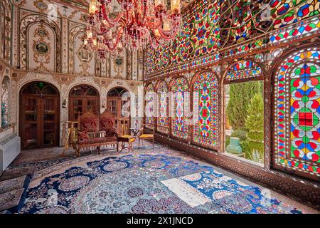 Intérieur orné de la salle de réception (shahneshin) avec de grands vitraux colorés dans la Maison historique de Mollabashi à Ispahan, Iran. Banque D'Images