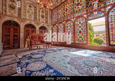 Vue intérieure du shahneshin (une salle de réception dédiée) avec de grands vitraux colorés dans la Maison historique de Mollabashi à Ispahan, Iran Banque D'Images