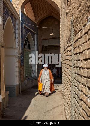 Un iranien vêtu de vêtements religieux musulmans traditionnels marche dans une ruelle étroite du Grand Bazar d'Ispahan, en Iran. Banque D'Images