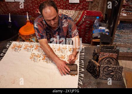 Le bloc artisanal Ghalamkar (art traditionnel iranien de l'imprimerie textile) imprime un motif complexe sur un tissu de coton avec un tampon en bois. Ispahan, Iran. Banque D'Images