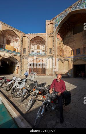 Un homme tourne la clé pour démarrer le moteur de sa moto garée à la porte Qeysarie, la porte d'entrée du Grand Bazar sur la place Naqsh-e Jahan. Ispahan, Iran. Banque D'Images