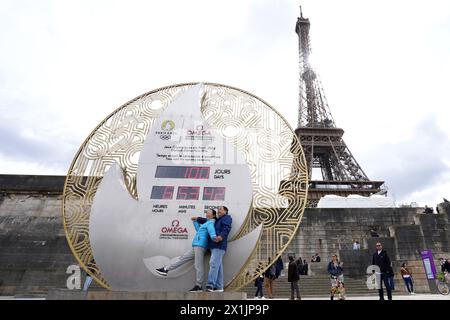 Une vue générale alors que les membres du public prennent des photos devant l'horloge à rebours du Port de la Bourfonnais près de la Tour Eiffel, Paris. Les Jeux Olympiques de 2024 débutent dans 100 jours dans la capitale française. Les Jeux commenceront le 26 juillet avec la première cérémonie d'ouverture qui se déroulera à l'extérieur d'un stade, chaque délégation nationale envoyant à la place 6 km sur l'artère principale de la ville avant de débarquer devant la Tour Eiffel. Date de la photo : mercredi 17 avril 2024. Banque D'Images