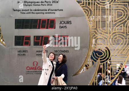 Une vue générale alors que les membres du public prennent des photos devant l'horloge à rebours du Port de la Bourfonnais près de la Tour Eiffel, Paris. Les Jeux Olympiques de 2024 débutent dans 100 jours dans la capitale française. Les Jeux commenceront le 26 juillet avec la première cérémonie d'ouverture qui se déroulera à l'extérieur d'un stade, chaque délégation nationale envoyant à la place 6 km sur l'artère principale de la ville avant de débarquer devant la Tour Eiffel. Date de la photo : mercredi 17 avril 2024. Banque D'Images