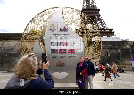 Une vue générale alors que les membres du public prennent des photos devant l'horloge à rebours du Port de la Bourfonnais près de la Tour Eiffel, Paris. Les Jeux Olympiques de 2024 débutent dans 100 jours dans la capitale française. Les Jeux commenceront le 26 juillet avec la première cérémonie d'ouverture qui se déroulera à l'extérieur d'un stade, chaque délégation nationale envoyant à la place 6 km sur l'artère principale de la ville avant de débarquer devant la Tour Eiffel. Date de la photo : mercredi 17 avril 2024. Banque D'Images