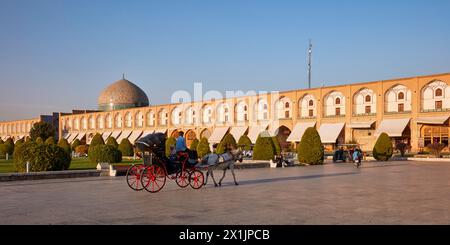 Une promenade circulaire dans une calèche tirée par des chevaux – activité touristique populaire sur la place Naqsh-e Jahan, site classé au patrimoine mondial de l’UNESCO. Ispahan, Iran. Banque D'Images