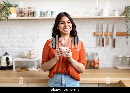 Femme joyeuse du moyen-Orient debout dans la cuisine moderne Banque D'Images