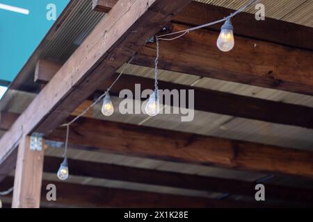 Une chaîne de lumières est suspendue à une poutre en bois robuste, ajoutant une ambiance chaleureuse à la zone ombragée ci-dessous. La structure en bois dur est accentuée avec WO Banque D'Images