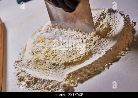 Préparation de cuisson avec farine et grattoir de banc, détail main gantée Banque D'Images