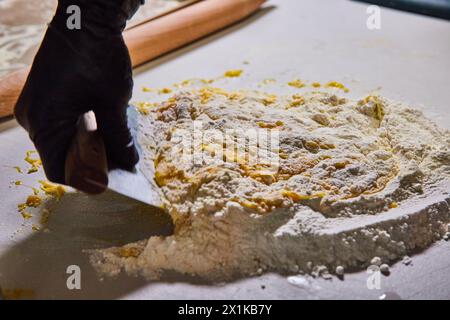 Préparation de pâte à pâtes maison, main gantée avec couteau, vue de dessus Banque D'Images