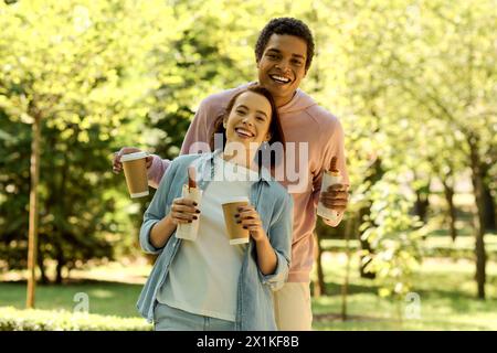 Couple diversifié dans une tenue vibrante dégustant un café ensemble dans le parc par une journée lumineuse. Banque D'Images