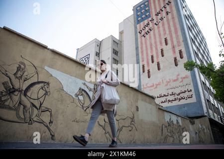 Téhéran, Iran. 14 avril 2024. Une femme passe devant une fresque murale lisant "à bas les États-Unis" à Téhéran, en Iran, le dimanche 14 avril 2024. Israël a salué dimanche ses défenses aériennes face à une attaque sans précédent de l’Iran, affirmant que les systèmes ont contrecarré 99% des plus de 300 drones et missiles lancés vers son territoire. (Photo de Sobhan Farajvan/Pacific Press/Sipa USA) crédit : Sipa USA/Alamy Live News Banque D'Images
