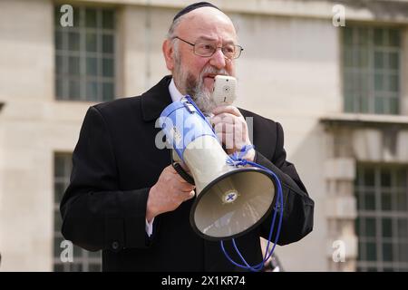 Le grand rabbin Ephraïm Mirvis parle à l'installation de Empty Seder table, une table à manger vide pour Seder avec 133 chaises vides avec des affiches d'otages juifs détenus par le Hamas dans le conflit israélo-Hamas, qui a été mis en place par le UK Hostages Families Forum à Richmond Terrace à Westminster, Londres. Date de la photo : mercredi 17 avril 2024. Banque D'Images