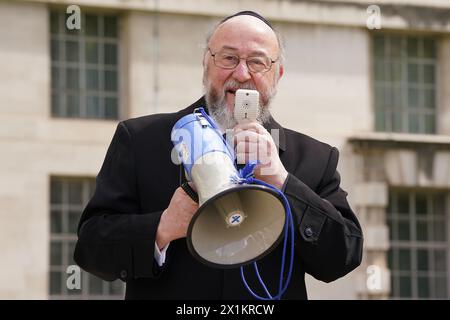 Le grand rabbin Ephraïm Mirvis parle à l'installation de Empty Seder table, une table à manger vide pour Seder avec 133 chaises vides avec des affiches d'otages juifs détenus par le Hamas dans le conflit israélo-Hamas, qui a été mis en place par le UK Hostages Families Forum à Richmond Terrace à Westminster, Londres. Date de la photo : mercredi 17 avril 2024. Banque D'Images