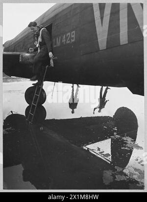 LE LANCASTER III [un développement du type de bombardier Lancaster antérieur]. - Photo (publiée en 1944) montre - Une curieuse étude en réflexions. Deux membres de l'équipage au sol d'un Lancaster II se tiennent à son point de dispersion baigné de pluie, la Royal Air Force Banque D'Images