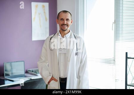 Portrait d'un médecin mature souriant portant une blouse de laboratoire debout dans son bureau Banque D'Images